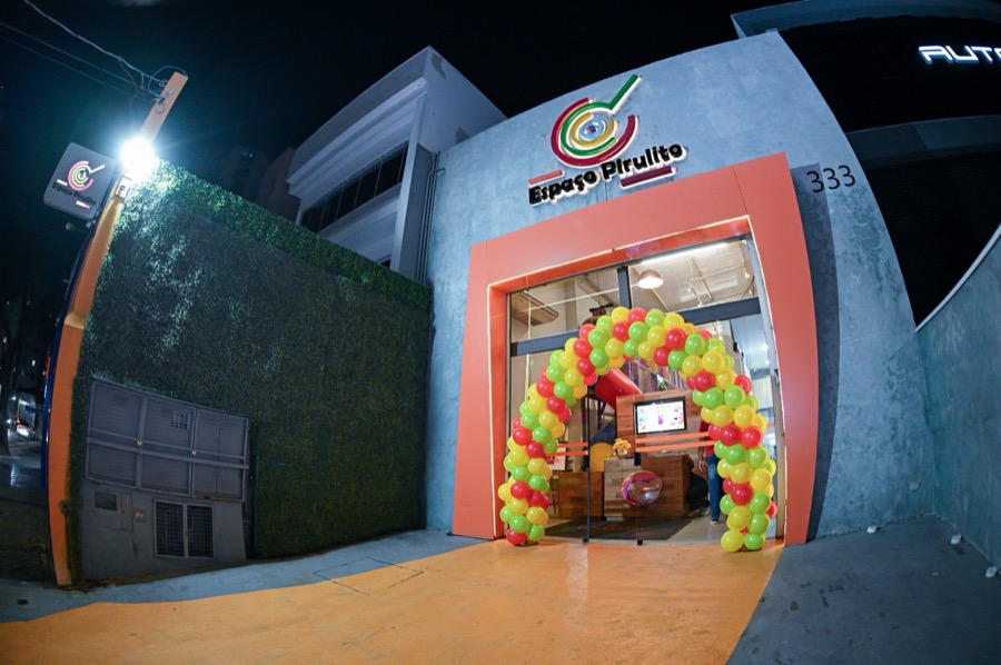 Fachada do Espaço Pirulito à noite com arco de balões